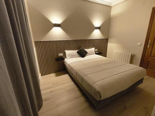 a bedroom with a bed with a black cat sitting on it at Hostal El Cruce in Paracuellos de Jarama