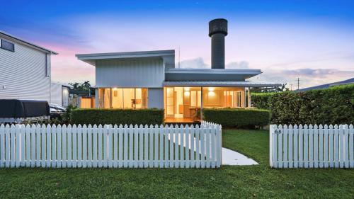 a white picket fence in front of a house at White Cockatoo Beachfront Cottage in Newell Beach