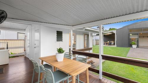 a house with a deck with a table and chairs at White Cockatoo Beachfront Cottage in Newell Beach