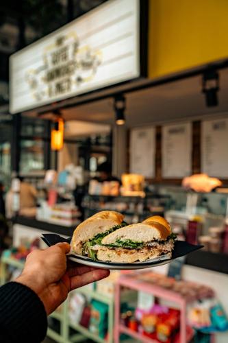 a person holding a plate with a sandwich on it at The Social Hub Maastricht in Maastricht