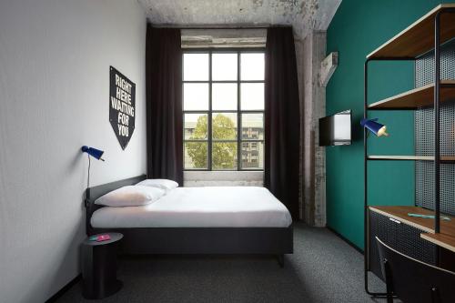 a small bedroom with a bed and a window at The Social Hub Maastricht in Maastricht