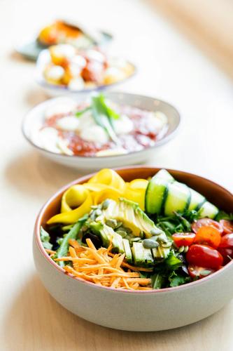a bowl of salad on a table with other plates of food at The Social Hub Delft in Delft
