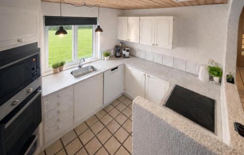 a kitchen with white cabinets and a sink and a window at Nice Home In Oksbøl With Sauna in Oksbøl