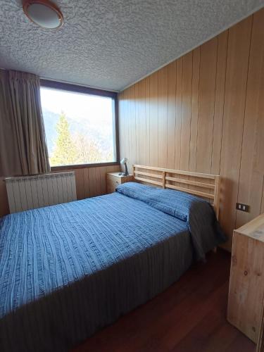 a bedroom with a bed and a large window at Marilleva 1400 - Alpine Apartment in Marilleva
