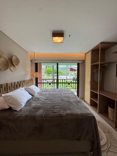 a bedroom with a large bed and a large window at Chalé Mar e Sol, Marina e Resort Angra in Angra dos Reis