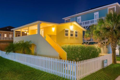 a yellow house with a white fence in front of it at Pompano Beachview Home home in South Padre Island