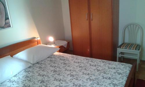 a small bedroom with a bed and a chair at Apartman Sulić in Podgora