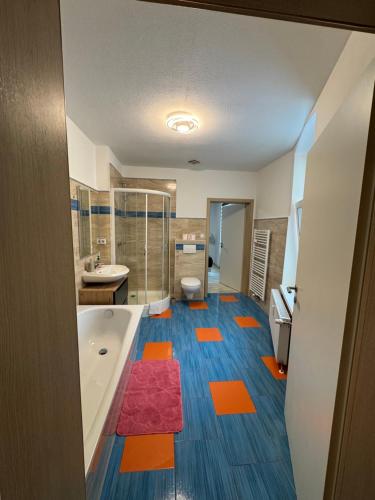 a bathroom with orange and blue floors and a tub at Ferienwohnung Florion 2 in Bernburg
