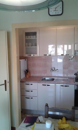 uma cozinha com armários brancos e um frigorífico branco em Apartman Sulić em Podgora