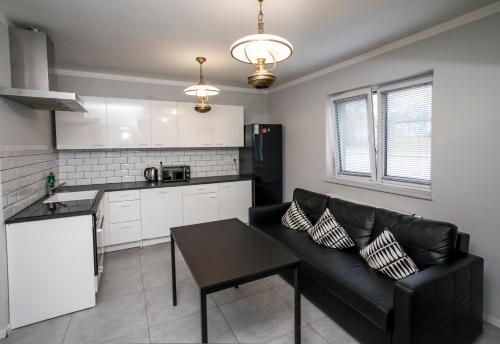 a living room with a black couch and a kitchen at Mia Mia House in Katowice