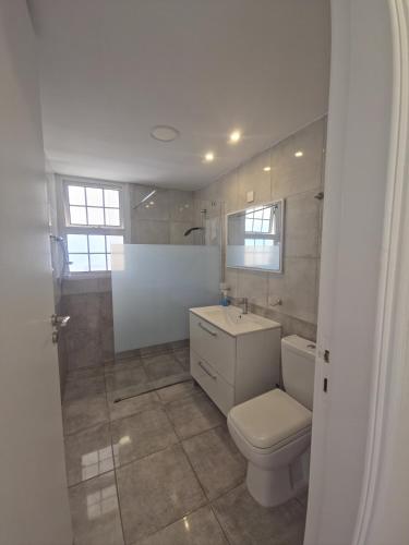 a white bathroom with a toilet and a sink at 2 bedroom home sea view in Pyla