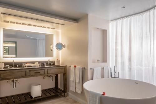 a bathroom with a tub and a sink and a mirror at BodyHoliday St Lucia - All Inclusive in Gros Islet