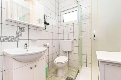 a white bathroom with a toilet and a sink at Apartments Miljenko in Dobropoljana