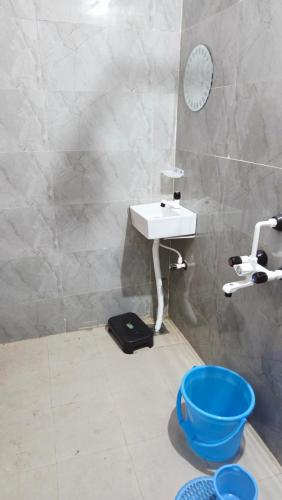 a bathroom with a sink and a blue bucket at Radha Rani Guest House in Sīkar