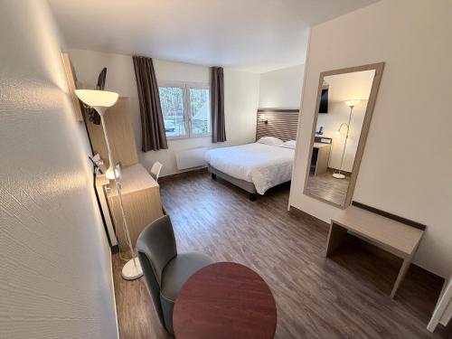 a hotel room with a bed and a mirror at Hotel ARBOR - Les Hunaudieres - Le Mans Sud - Mulsanne in Mulsanne
