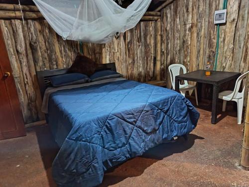 a bedroom with a bed with a blue comforter and a table at Rústico y Natural in Estación El Salto