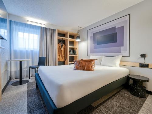 a hotel room with a large bed with a bag on it at Ibis Orly Chevilly Tram 7 in Chevilly-Larue