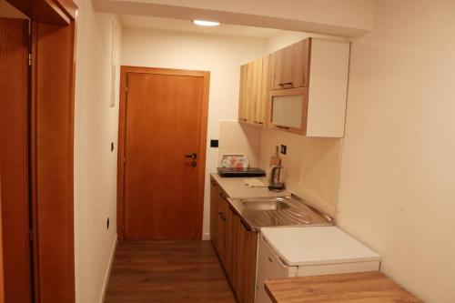 a small kitchen with a sink and a wooden door at Apartments Kenan in Plav