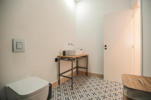 a small bathroom with a toilet and a table at Republica House in Trafaria