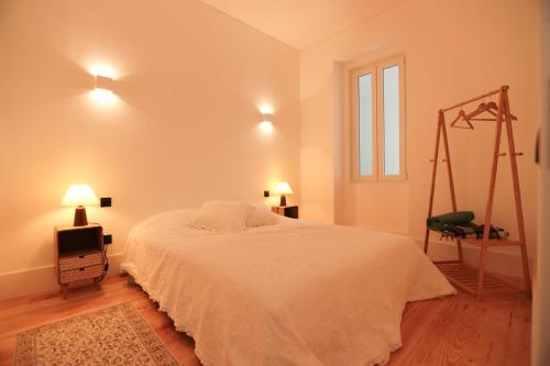 a bedroom with a white bed and a chair at Republica House in Trafaria