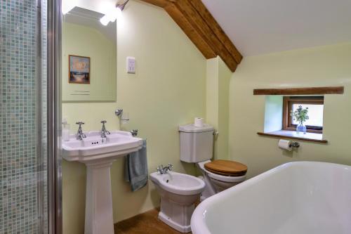 a bathroom with a sink and a toilet and a tub at Finest Retreats - Oak Leaf Cottage in Beaworthy