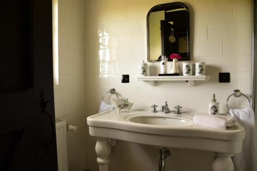 un bagno bianco con lavandino e specchio di Cottage Nostalgia a Damme