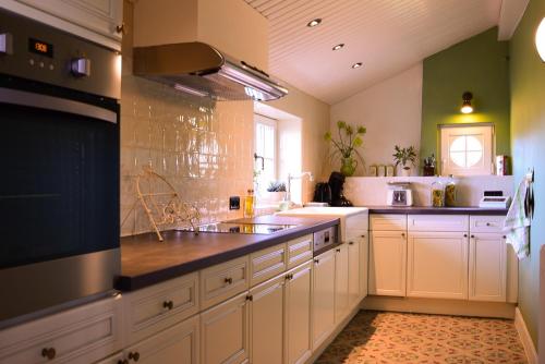 una grande cucina con mobili bianchi e un lavandino di Cottage Nostalgia a Damme