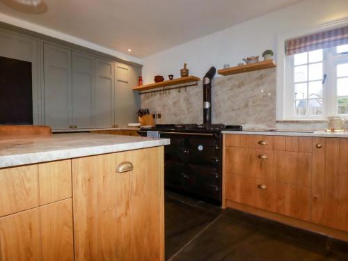 a kitchen with wooden cabinets and a black stove at Vosporth Villa in Newquay