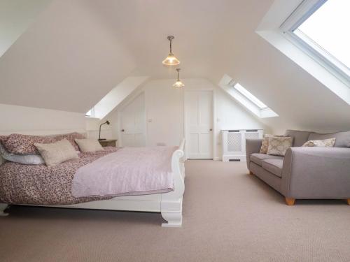 a white bedroom with a bed and a couch at Vosporth Villa in Newquay