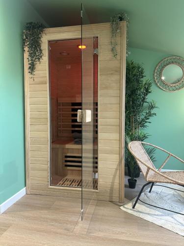 a glass shower in a room with a chair at Jungle Suite - Sauna et Relaxation in Arras