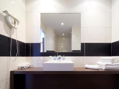 a bathroom with a sink and a mirror at Kyriad Grenoble Centre in Grenoble