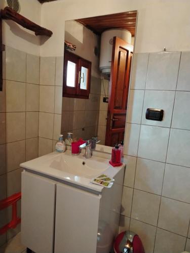 a bathroom with a white sink and a mirror at La maison d'amour in Sanluri