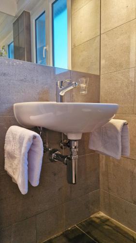 a sink in a bathroom with a mirror and towels at Swiss Lakeside Apartments in Spiez