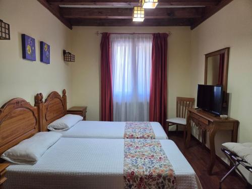 a hotel room with two beds and a television at Hotel Rural Las Farolas in San Rafael