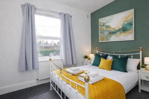 a bedroom with a bed with yellow and green pillows at Falklands street City centre House-Free Parking in York