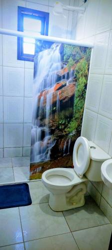 a bathroom with a toilet and a painting on the wall at Casacapuba Jacaraipe Es in Serra