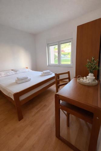 a bedroom with a bed and a table and a window at Apartmani Čop Rab in Banjol