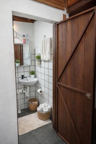 a bathroom with a wooden door and a sink at Chalé do Ben in São Thomé das Letras