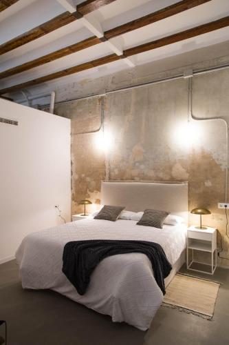 a bedroom with a large white bed and two lamps at Can Turia in Valencia
