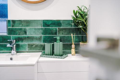 a bathroom with a sink and a green tiled wall at Westminster Apartments by YourStays in Crewe