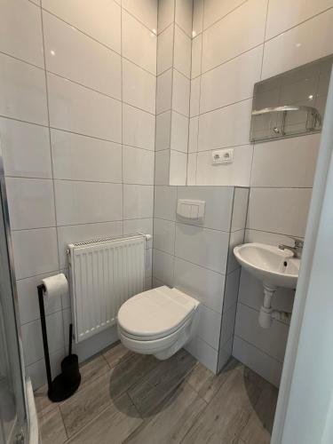 a white bathroom with a toilet and a sink at Apartamenty Rybna 1 Centrum in Tarnów
