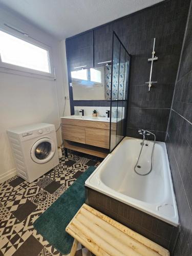 a bathroom with a tub and a washing machine at L'Atelier Eiffel Moderne & confortable in Saint-Brieuc