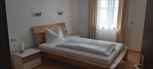 a bedroom with a bed with white sheets and a window at Pension Post - Sistrans in Innsbruck
