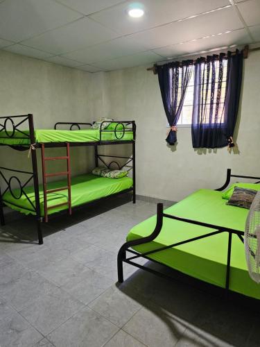 a room with two bunk beds with green sheets at Honey Beach House in La Esmeralda