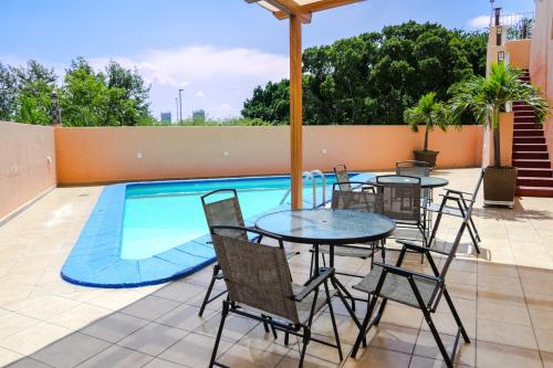 a patio with tables and chairs next to a swimming pool at Hotel Santa Irene Guadalajara in Guadalajara