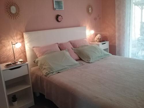 a bedroom with a bed with pink and white pillows at gîte La Valentina, 3 étoiles, de plain-pied et climatisé in Cubjac