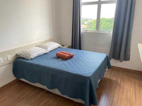 a bedroom with a blue bed with two pillows on it at Flats da Júnia, ótimo benefício, fácil check-in, wifi , tv, ar, garagem, localizacao in Lagoa Santa