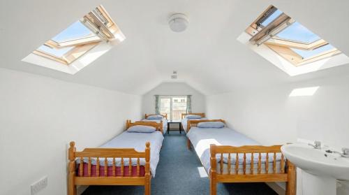a row of beds in a room with skylights at Breakwater Hostel in Newquay