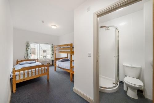 a bathroom with a shower and a toilet and a bed at Breakwater Hostel in Newquay