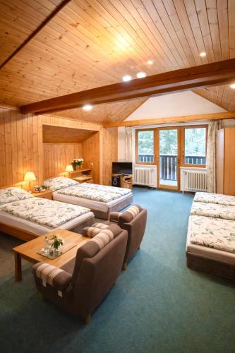 a room with four beds and a table and chairs at Penzion Pstruh Stožec in Stožec